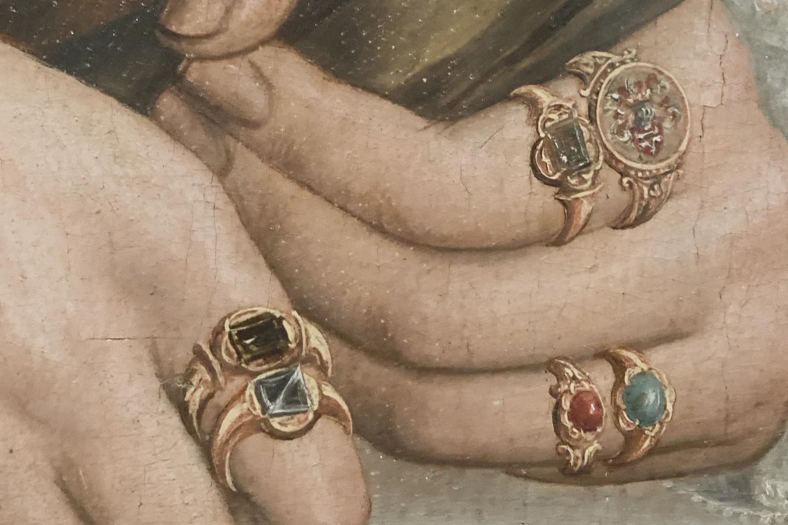Detail of a painting of two hands wearing gold rings set with coloured stones.