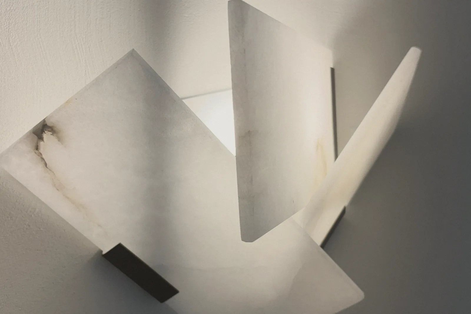 Folded white panels catching soft light against a grey wall.