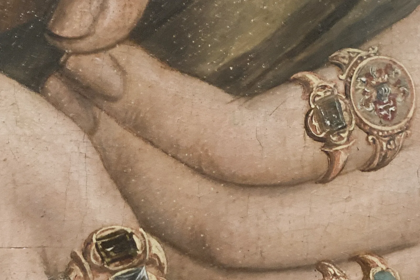 Painted detail of hands and wrists with gold rings.