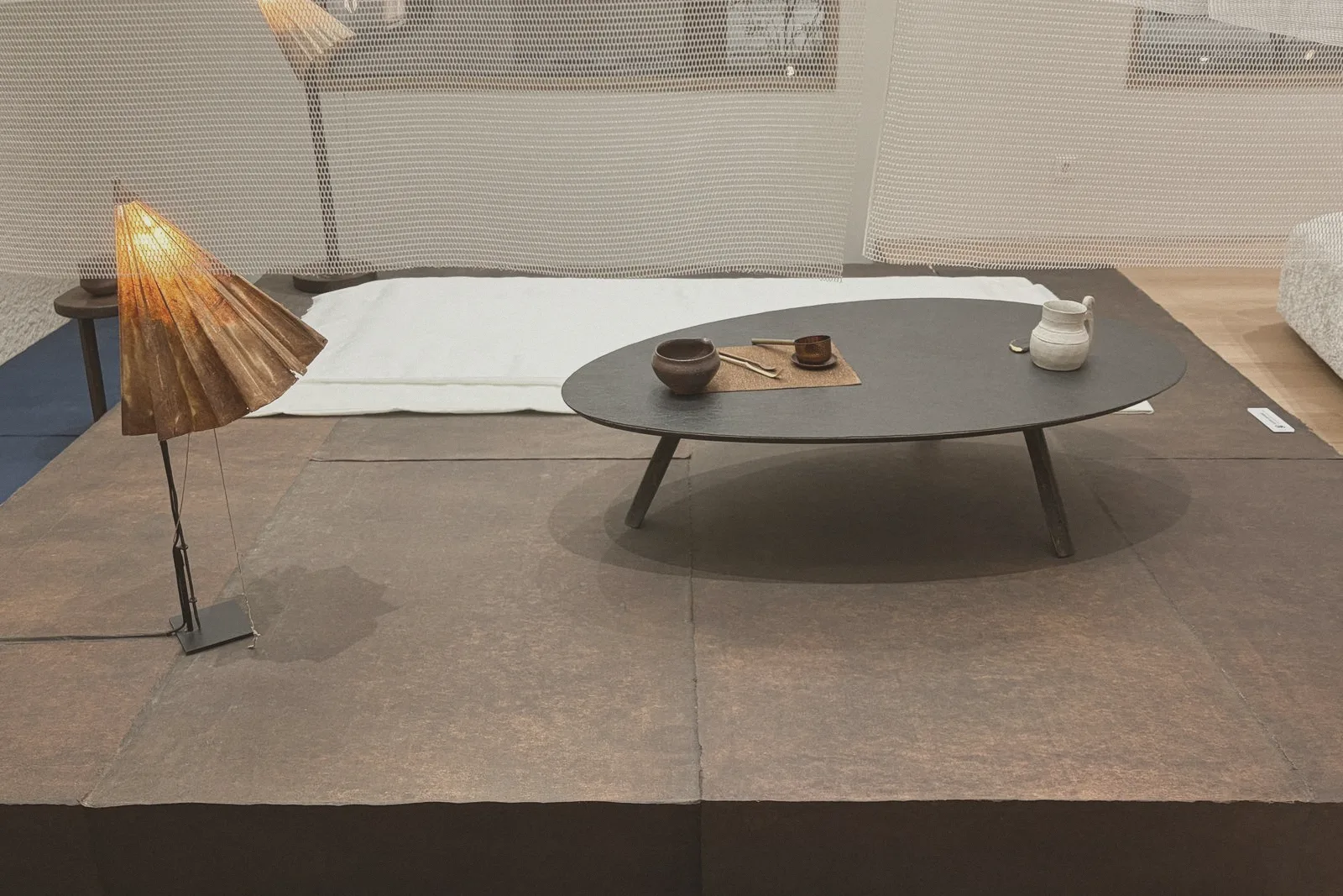 A table lamp on a low stone table in a quiet gallery room.